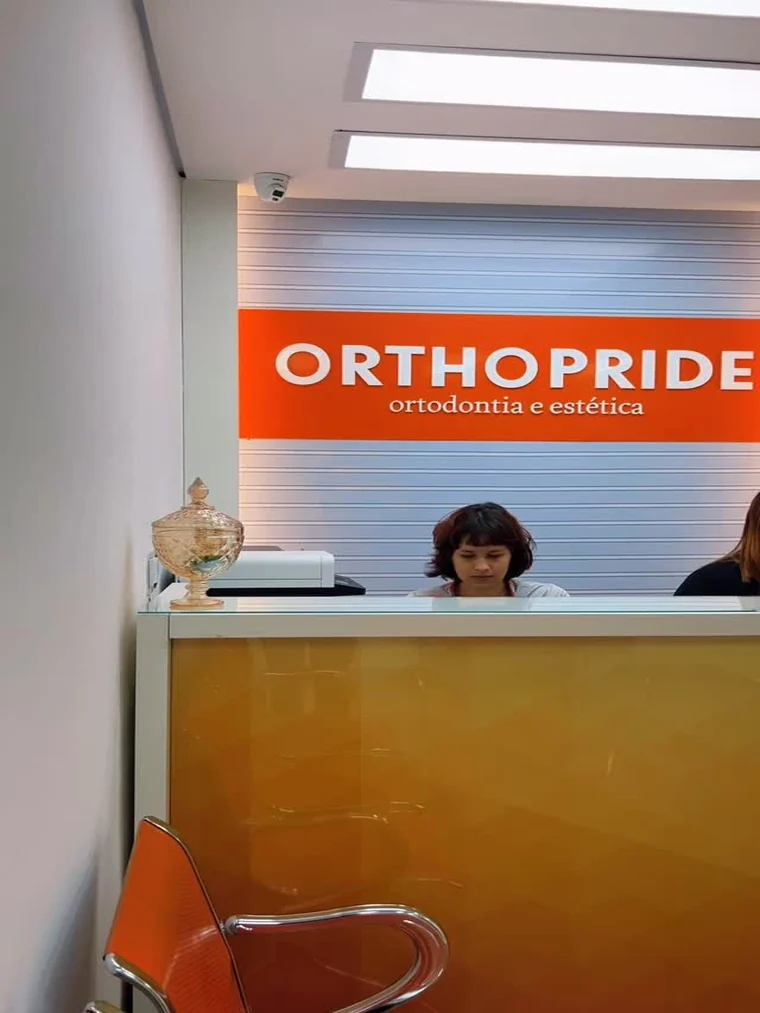 Recepção da Orthopride de Ribeirão das Neves, com o letreiro da marca atrás do balcão